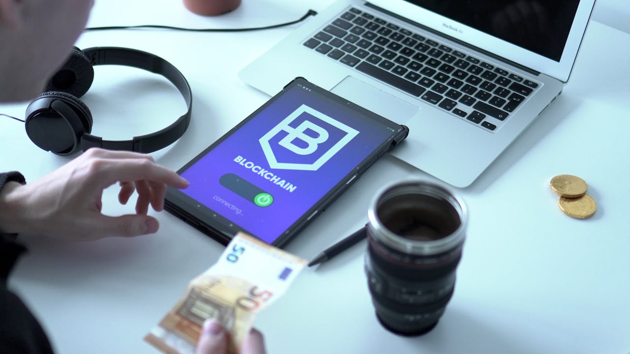 Close-up of digital currency transaction using blockchain technology on tablet with laptop and euro bills.